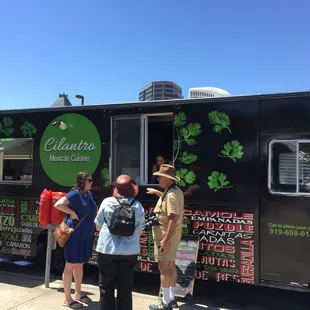 a group of people standing in front of a food truck