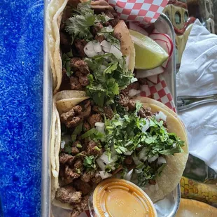 a tray of tacos and salsa