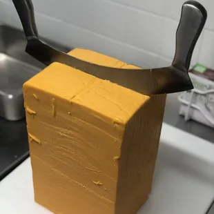 Tools of the trade for cutting through large blocks of Wisconsin cheddar cheese.
