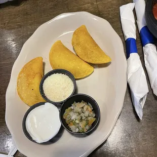 Chicken empanadas, with side of  sour cream, cheese, and dice tomatoes salad