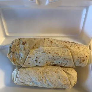two burritos in a styrofoam container