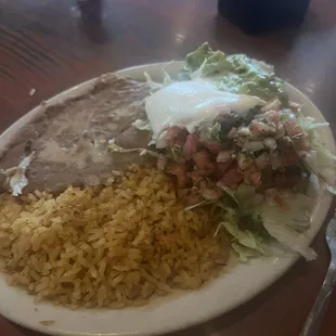 Healthy portions of fajita sides (refried beans, rice, guacamole, sour cream, lettuce, and cheese)