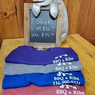 a pile of shirts and a chalkboard