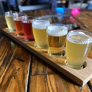 a flight of beers on a wooden tray