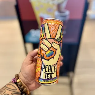 a hand holding a can of peace tea