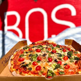 a box of pizza in front of a stop sign