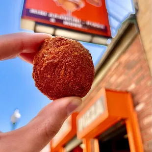 a hand holding a donut outside a donut shop