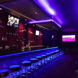 a bar with stools and neon lights