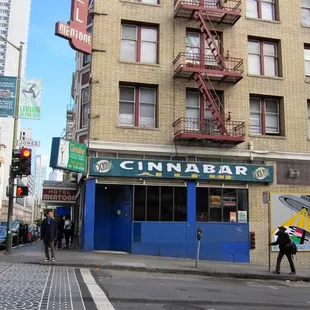 people walking on the sidewalk in front of a building