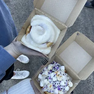 a person holding two boxes of food