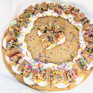 Cookie cake with cake batter frosting, cookie dough, cookie chunks, and sprinkles