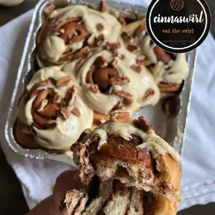 a hand holding a cinnamon roll