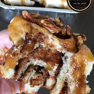 a hand holding a cinnamon roll