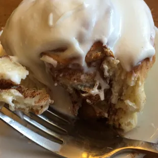 a cinnamon roll with icing and a bite taken out of it