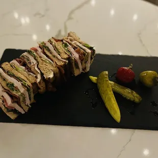 a club sandwich with pickles and a pickle