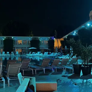 a man sitting at a table in the middle of a pool at night