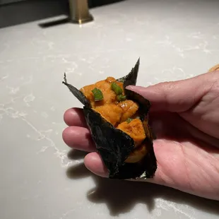 a hand holding a piece of sushi