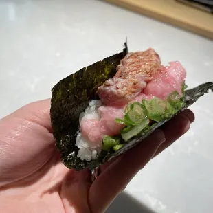 a hand holding a piece of sushi