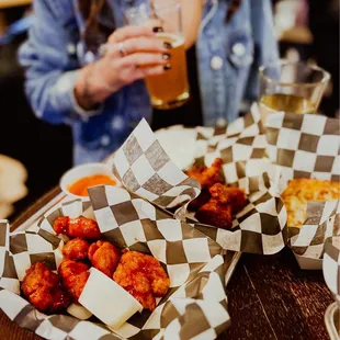 a woman sitting at a table with a tray of food and a glass of beer