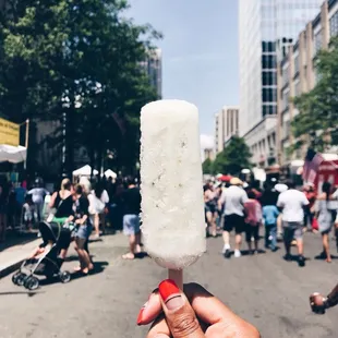 a person holding a popsicle in the middle of the street