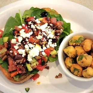 a white plate with a salad and a bowl of fried tater tots