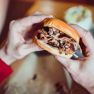 a person holding a pulled pork sandwich