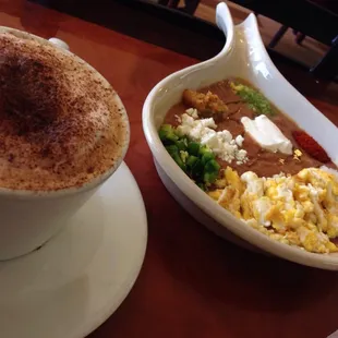 Ful with egg and cappuccino with chocolate powder on top. (delicious breakfast)