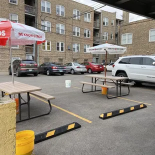 a parking lot with tables and umbrellas