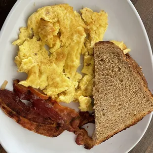 a plate of eggs, bacon and toast