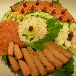 a platter of salmon, cucumbers, tomatoes, cucumbers, and