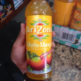 a person holding a bottle of arizona mango juice