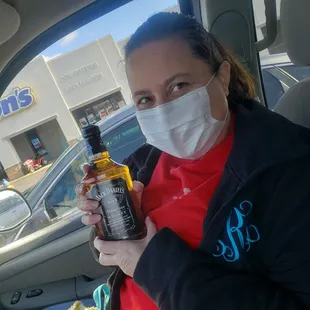 a woman in a mask holding a bottle of liquor