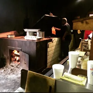 a man preparing food in front of a brick oven