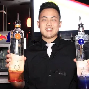 a bartender holding two bottles of alcohol
