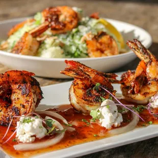 a plate of grilled shrimp and a bowl of salad