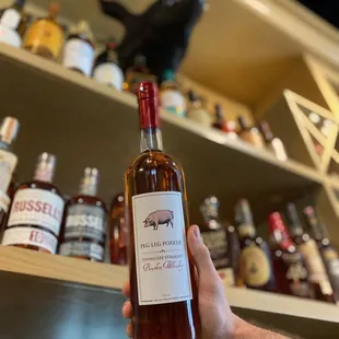 a hand holding a bottle of bourbon