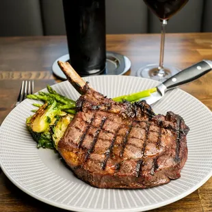 a steak on a plate with asparagus and a glass of wine