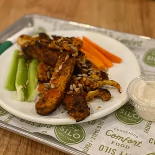 a plate of chicken wings, carrots, celery, and ranch dressing