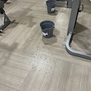 Buckets on floor next to equipment, and water all over the floor.