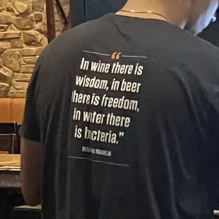 a man in a t - shirt that reads in wine there is wisdom, in beer here is freedom, in water