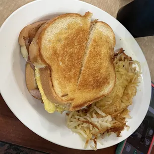 Sourdough bacon egg and cheese melt with hash browns on the side.