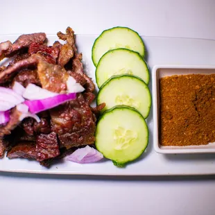 a plate of meat and cucumbers