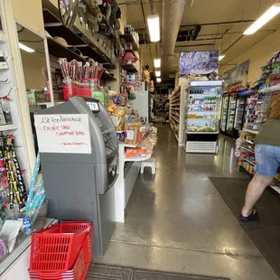 a woman walking down the aisle of a grocery store