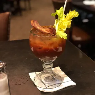 a bloody drink with bacon and celery garnish
