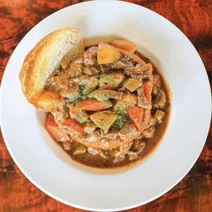 a bowl of stew with a piece of bread