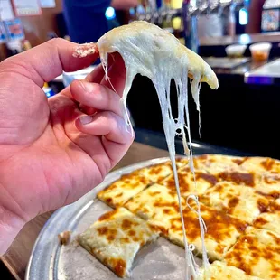 a hand holding a slice of cheese pizza