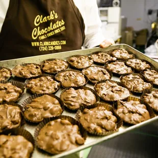 a baker holding a tray of chocolate muffins
