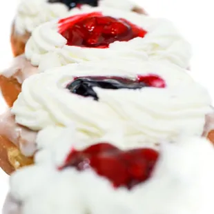 a row of doughnuts with cream frosting and berries
