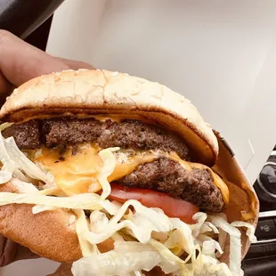 a hand holding a cheeseburger