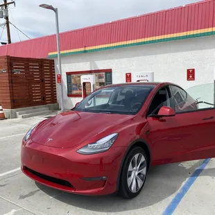 a red tesla model y parked in a parking lot